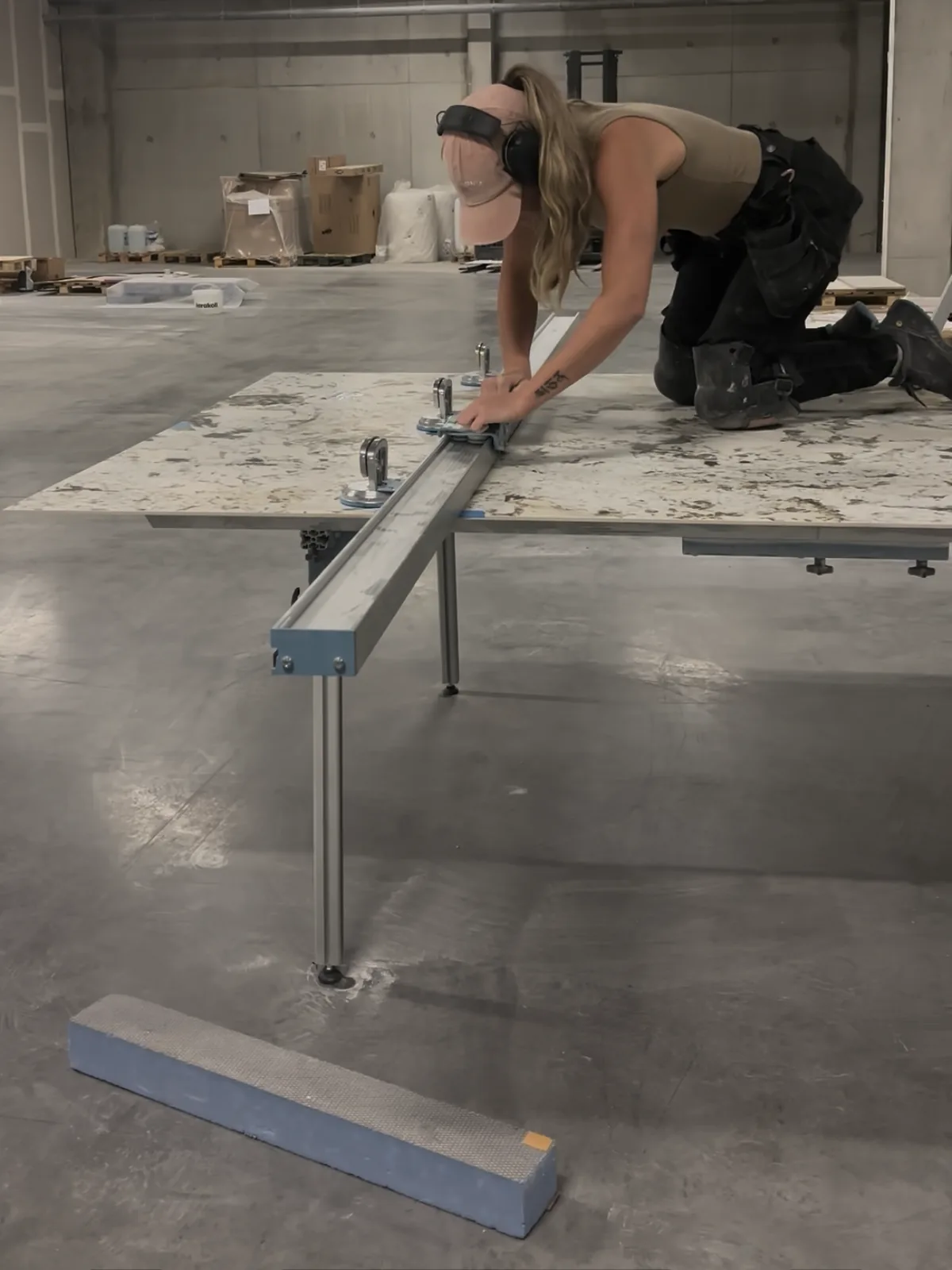 La carreleuse règle une plaque de grand format sur un chariot de manutention, en atelier.