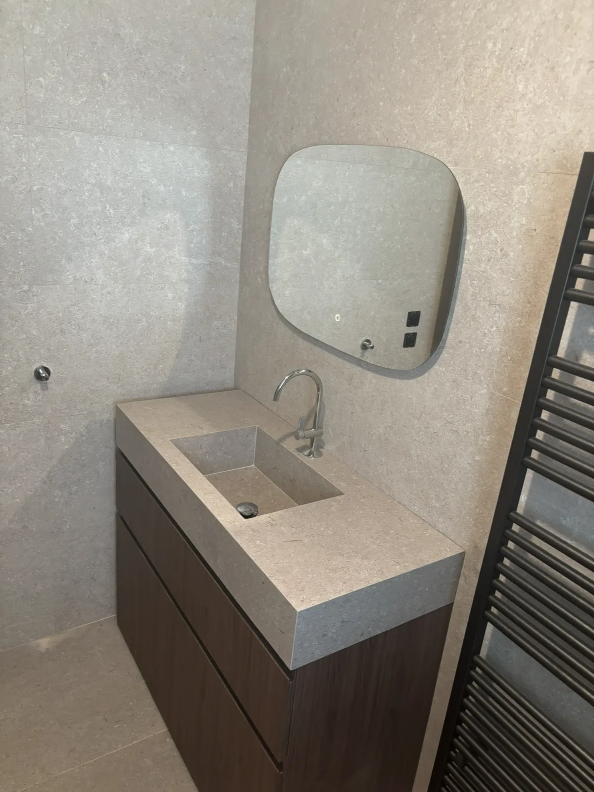 Vasque sur mesure taillée dans le même carrelage effet pierre que les murs.